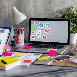 digital marketing workspace with a computer, desk, and office supplies and social media icons on the screen