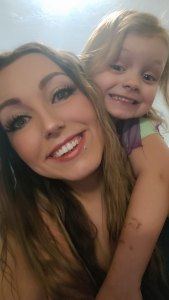 Harlee smiling for the camera wit her daughter on her back smiling as well